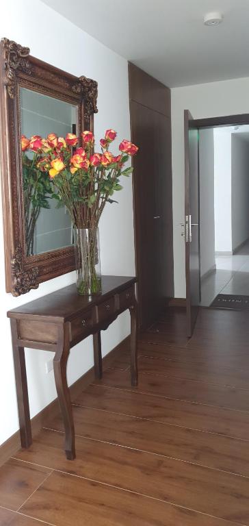 un jarrón de flores sobre una mesa con un espejo en LUXURY APARTMENT, EXCELLENT LOCATION, en Quito