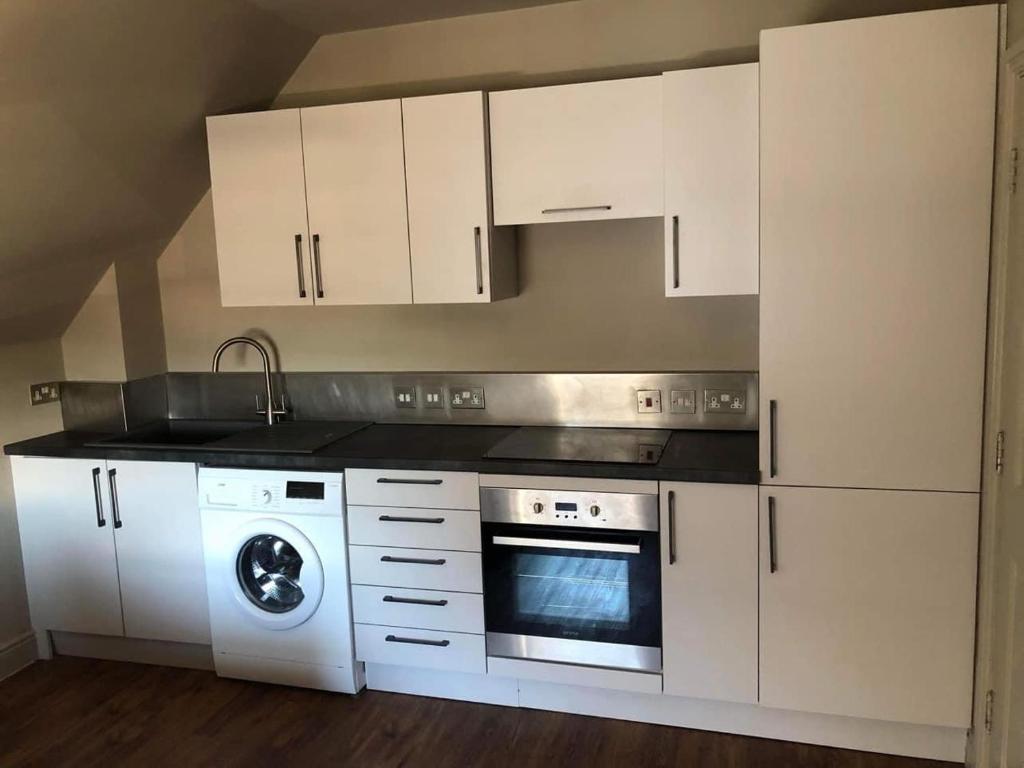 a kitchen with white cabinets and a washing machine at Mornington Harrogate in Harrogate