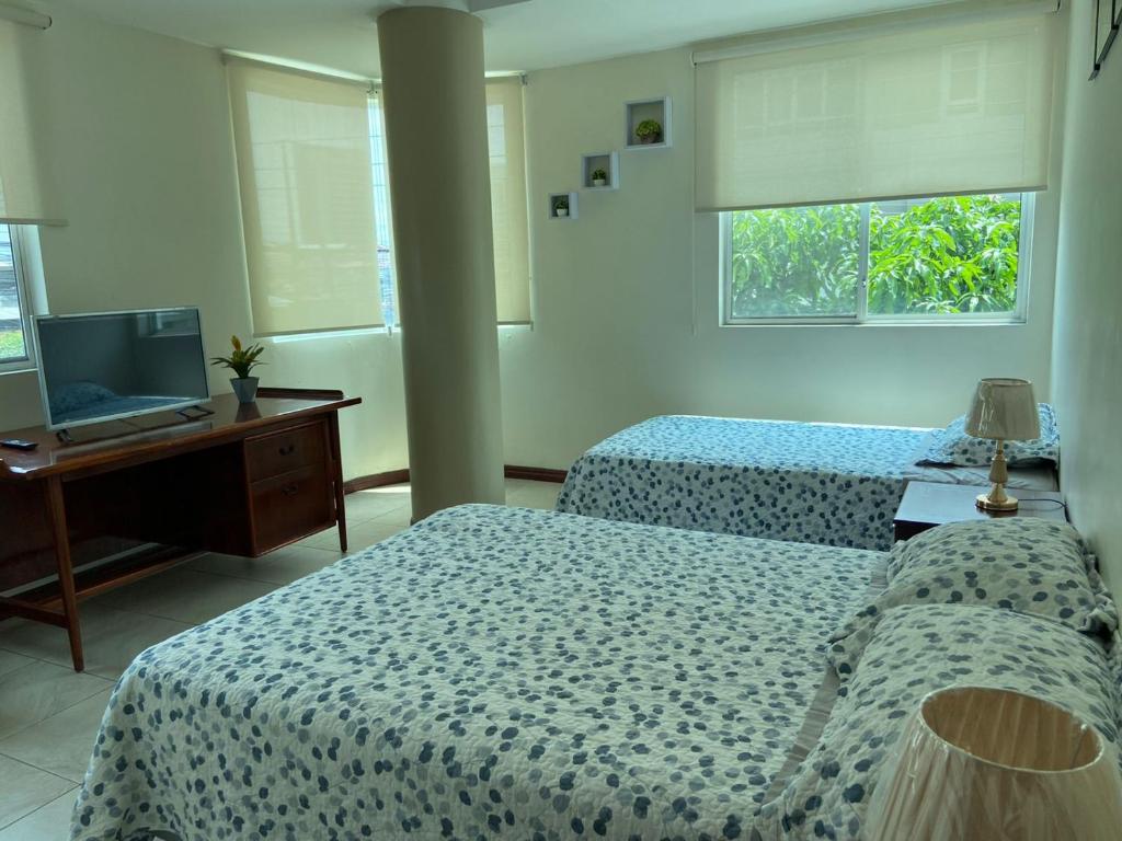 a bedroom with two beds and a desk and a computer at DORAL SUITE ¡CERCA DEL AEROPUERTO! in Guayaquil