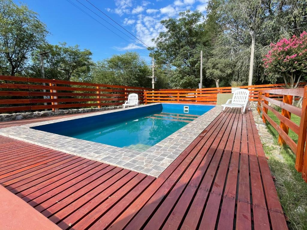 una piscina con 2 sillas y una terraza de madera en Casa Las Moras en San Antonio de Arredondo