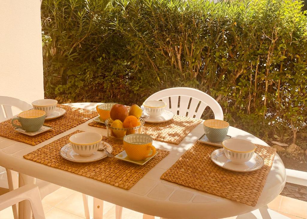 a table with cups and plates of food on it at Albufeira Praia São Rafael Sun Apartment in Albufeira