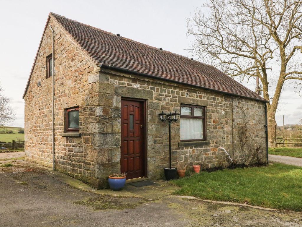 een klein bakstenen gebouw met een deur in het gras bij Hideaway in Leek