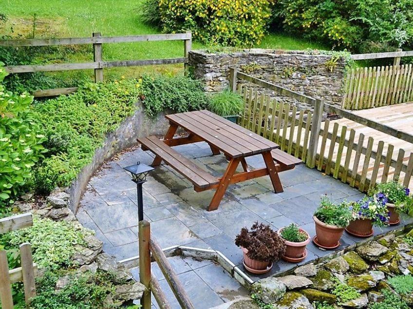 a wooden picnic table in a garden with potted plants at Mill Cottage in Fowey