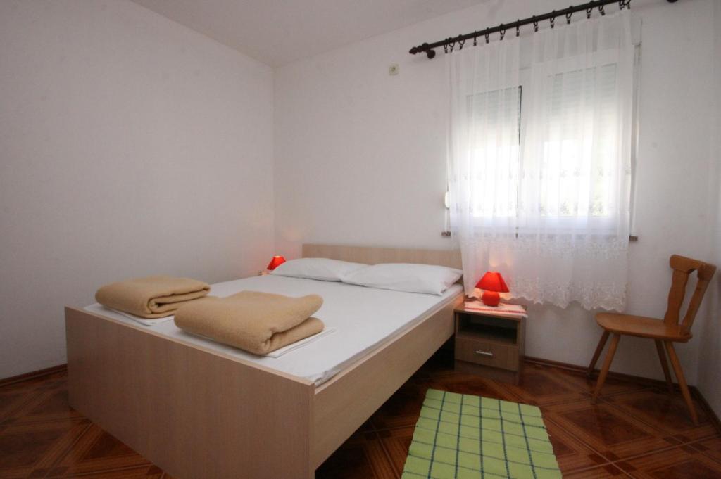 a bedroom with a bed and a chair and a window at Apartment Pag 6311c in Pag