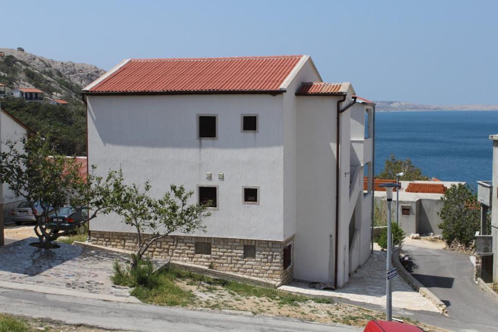 a white building with a red roof next to the ocean at Apartment Metajna 6337b in Zubovići