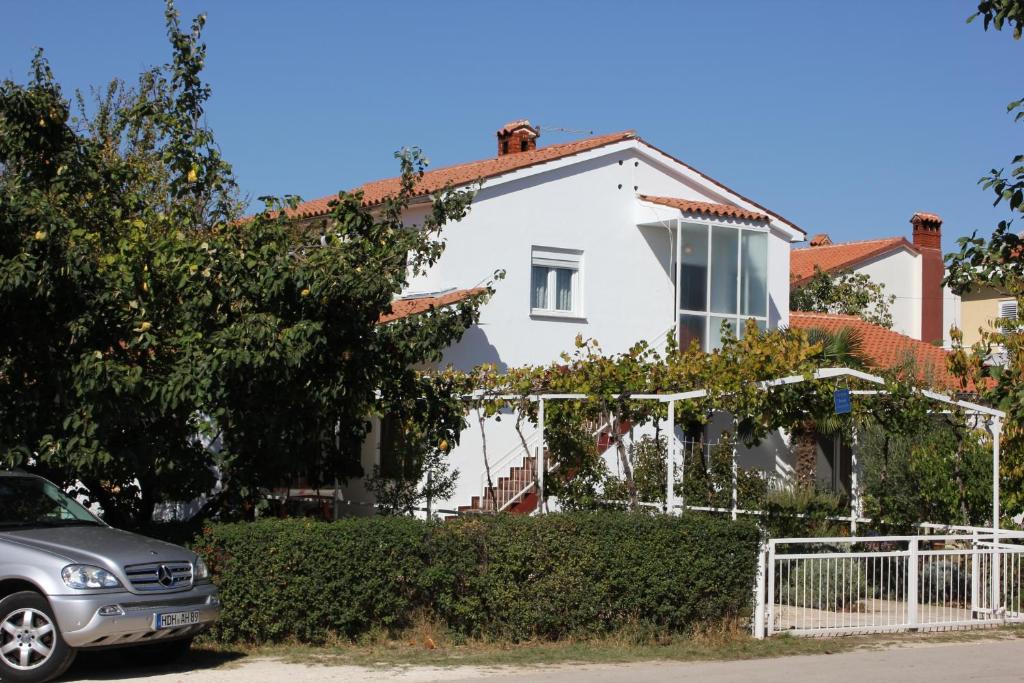 une maison blanche avec une voiture garée devant elle dans l'établissement Apartments with a parking space Valbandon, Fazana - 7228, à Fažana