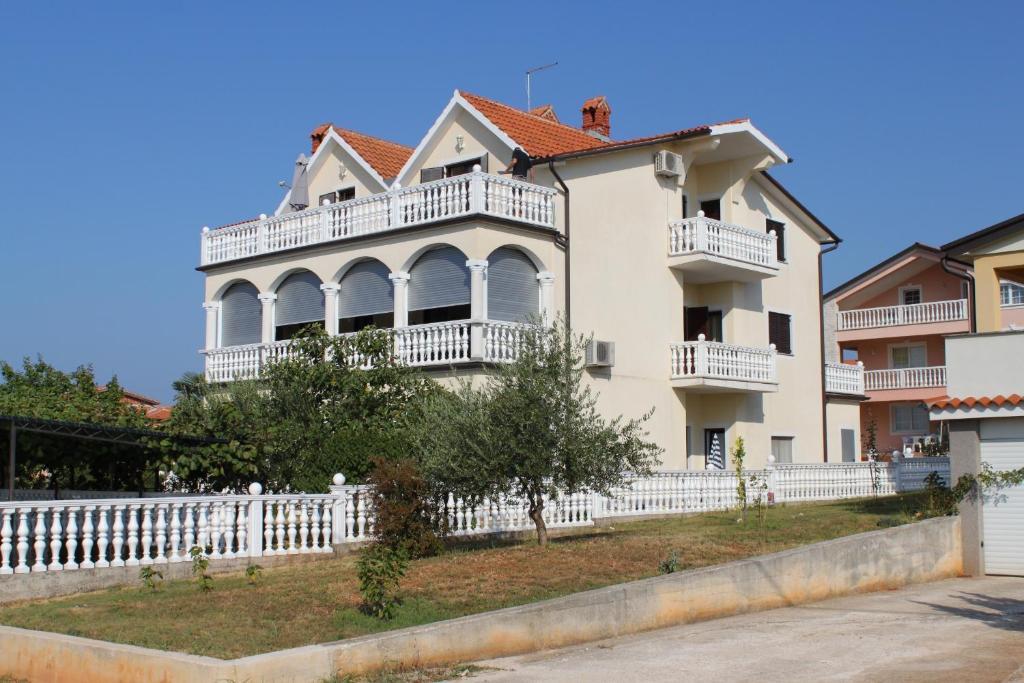 une grande maison blanche avec une clôture blanche dans l'établissement Apartments with a parking space Novigrad - 7037, à Novigrad