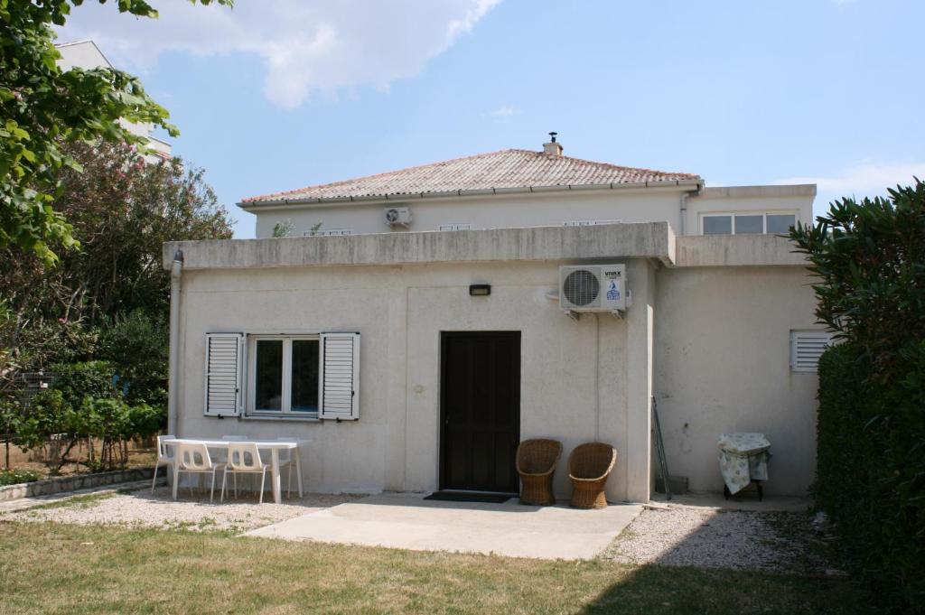 a small white house with a table and chairs at Apartments by the sea Pag - 6413 in Pag
