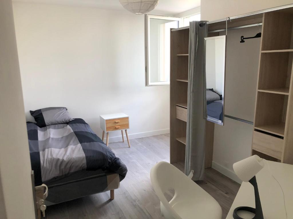 a bedroom with a bed and a desk with a chair at Évry time in Courcouronnes