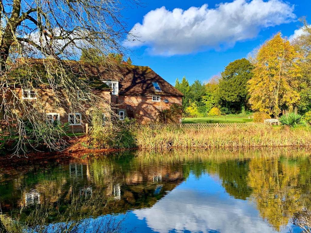 an old house reflected in the water of a lake at Moorhen Cottage in Hollingbourne