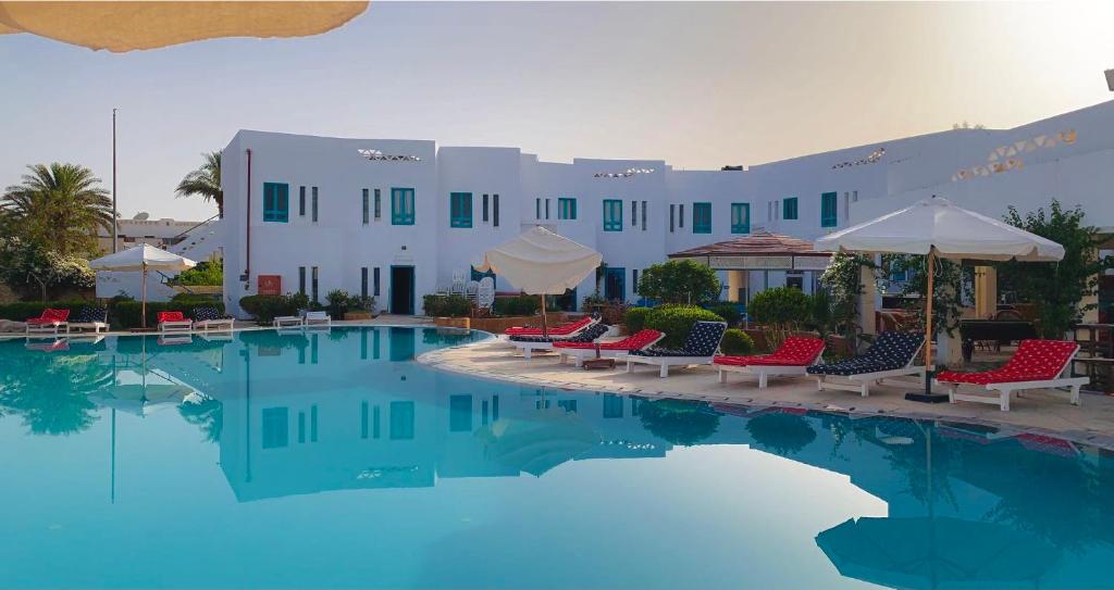 una piscina con sillas y sombrillas frente a un hotel en Sunset Hotel sharm El Sheikh en Sharm El Sheikh