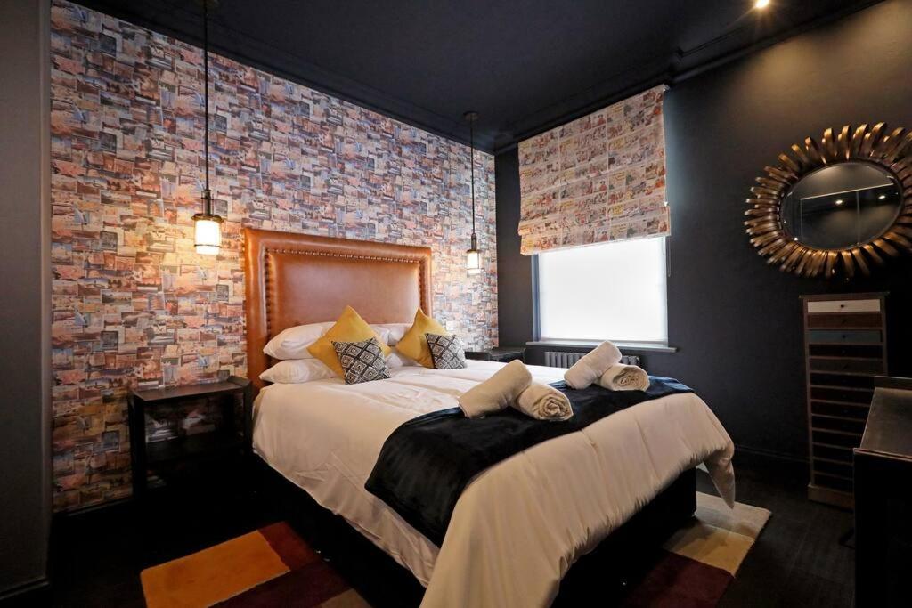 a bedroom with a large bed in a brick wall at Unique 2 Bed Apt With Parking - Ginger & Gold in Norwich