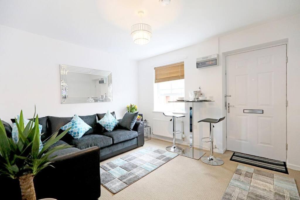 a living room with a black couch and a kitchen at Stafford Rest Ginger & Gold Ltd in Norwich