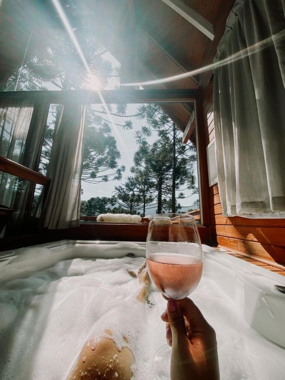 a person holding a glass of wine in a hot tub at Pousada Vale da Neve in Urubici