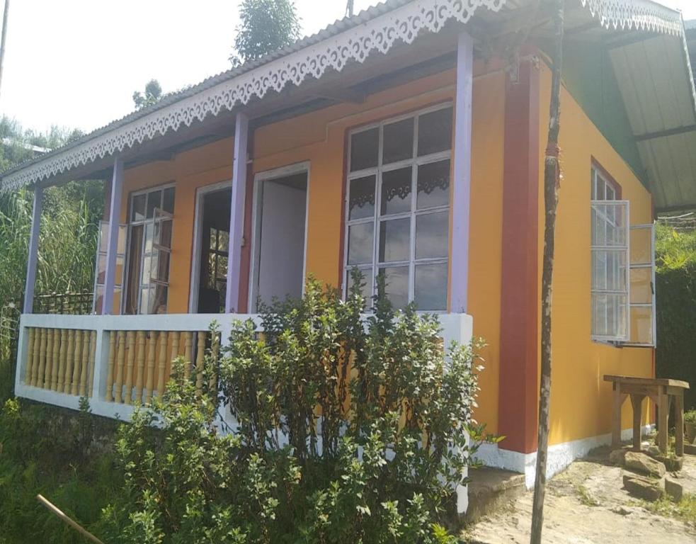 a small yellow and orange house with a porch at Chiten Homestay by StayApart in Sonāda