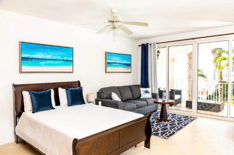 a bedroom with a bed and a living room with a couch at La Vista Azul - Lovely Spacious Condo close to Grace Bay - Free Wi-Fi in Turtle Cove
