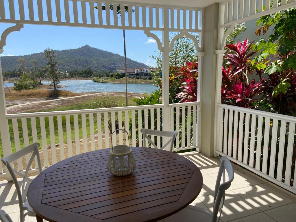 een houten tafel op een veranda met uitzicht op het water bij Lakeside Central Apartment in Townsville