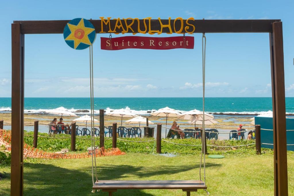 Marulhos Suítes Resort Muro Alto Beira Mar por Brevelar في بورتو دي غالينهاس: أرجوحة على شاطئ مع المحيط في الخلفية
