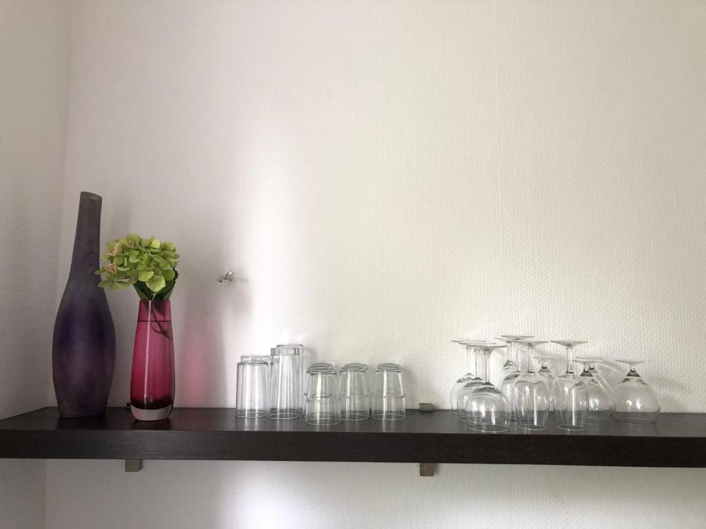 a shelf with glasses and a vase with flowers on it at studio e - Quiet central business one bedroom apartment for 3 guests in Düsseldorf