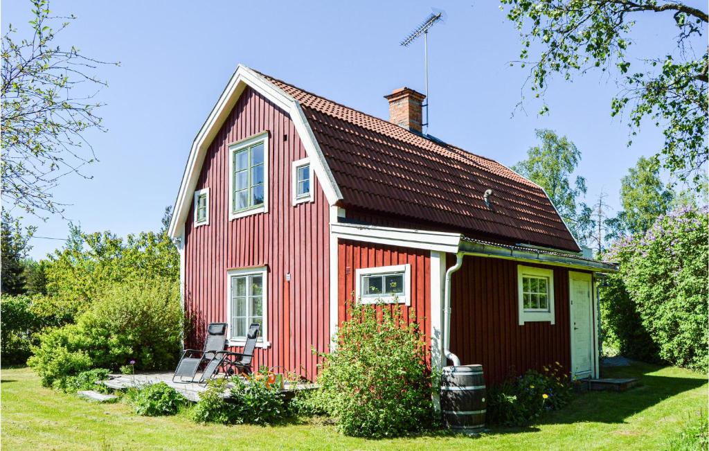 a red house with two chairs in the yard at Awesome Home In Hallstavik With Wifi in Hallstavik