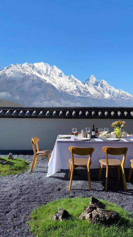 丽江丽江雪山奔鼓酒店（束河古镇店）的一张桌子和椅子,背景是群山
