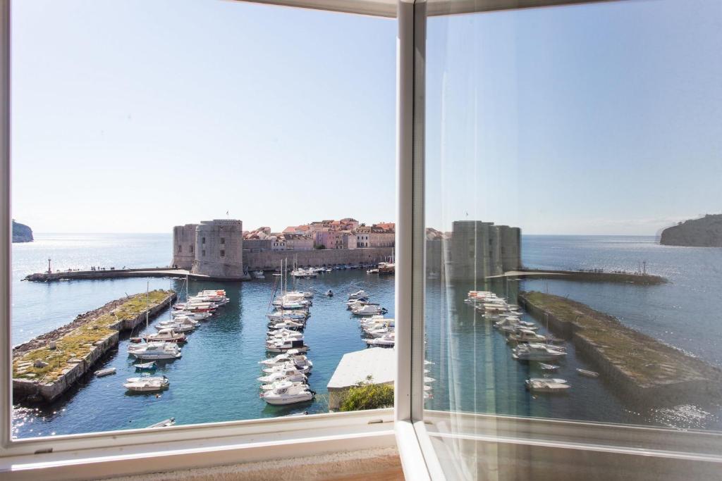 a window with a view of a harbor with boats at Dubrovnik Sunset Apartments in Dubrovnik