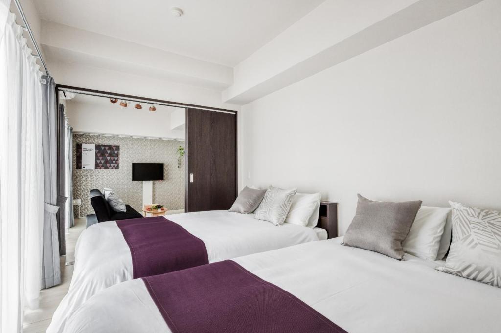 two beds in a room with white and purple at Bon condomium Umeda - Vacation STAY 8385 in Osaka