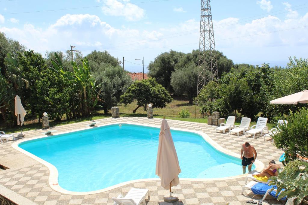 a swimming pool with chairs and an umbrella at Hotel Royal in Coccorino