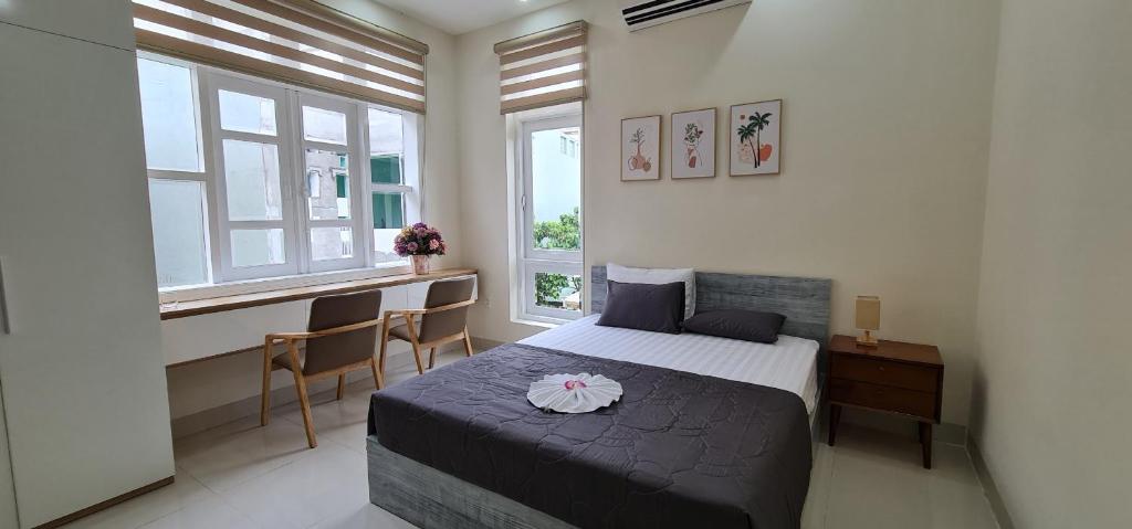 um quarto com uma cama, uma secretária e janelas em Châu Gia Villa Vũng Tàu - Có chỗ đậu xe hơi em Vung Tau