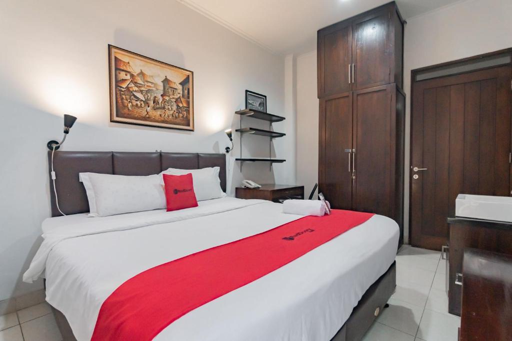 a bedroom with a large bed with a red blanket at RedDoorz at Dago Asri 3 in Bandung