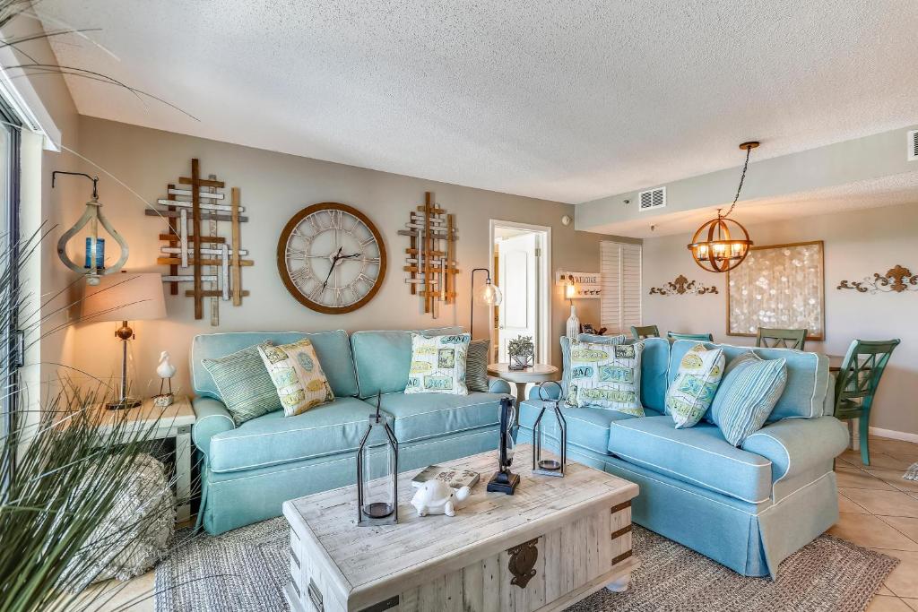 a living room with blue couches and a clock on the wall at Caprice 401 in St. Pete Beach