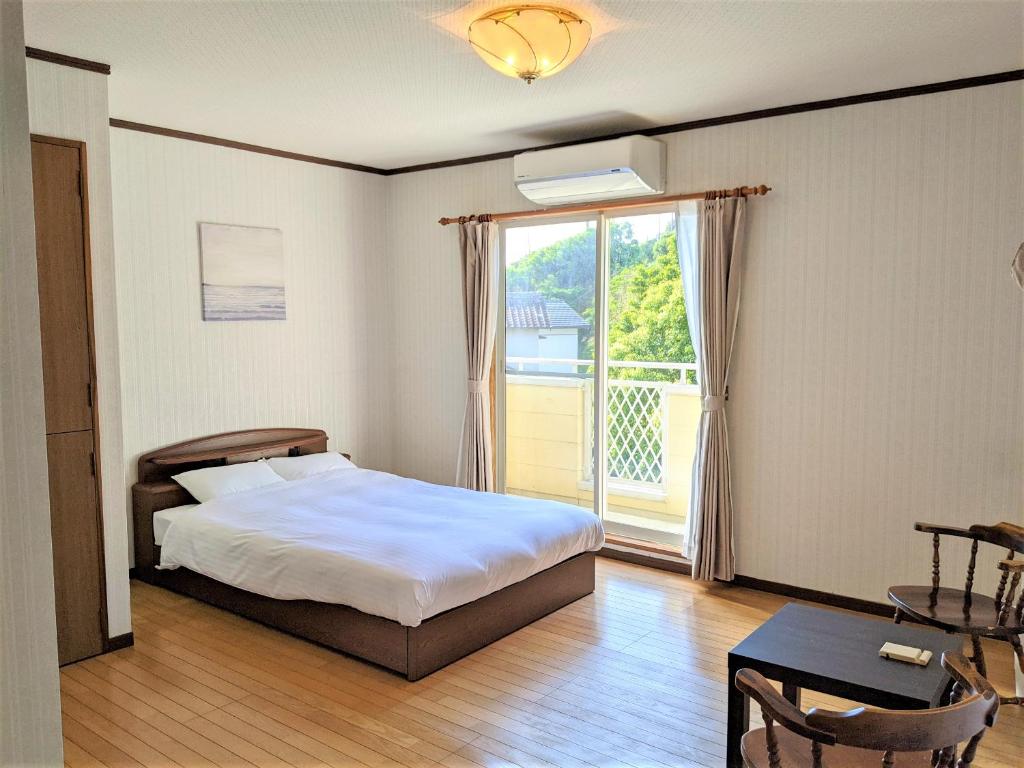 a bedroom with a bed and a large window at ritomaru house iki ashibe in Iki