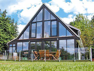 a house with glass windows and a table and chairs at Still Waters in Wroxham