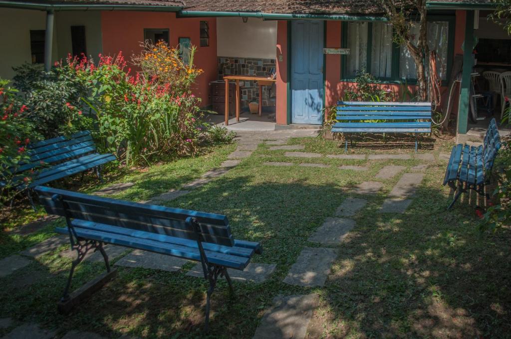 two blue benches sitting in front of a house at Pousada Flor do Mato in Lumiar