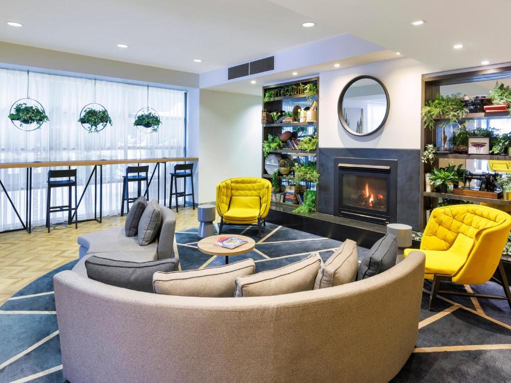 sala de estar con sofá, sillas y chimenea en Brady Apartment Hotel Flinders Street, en Melbourne