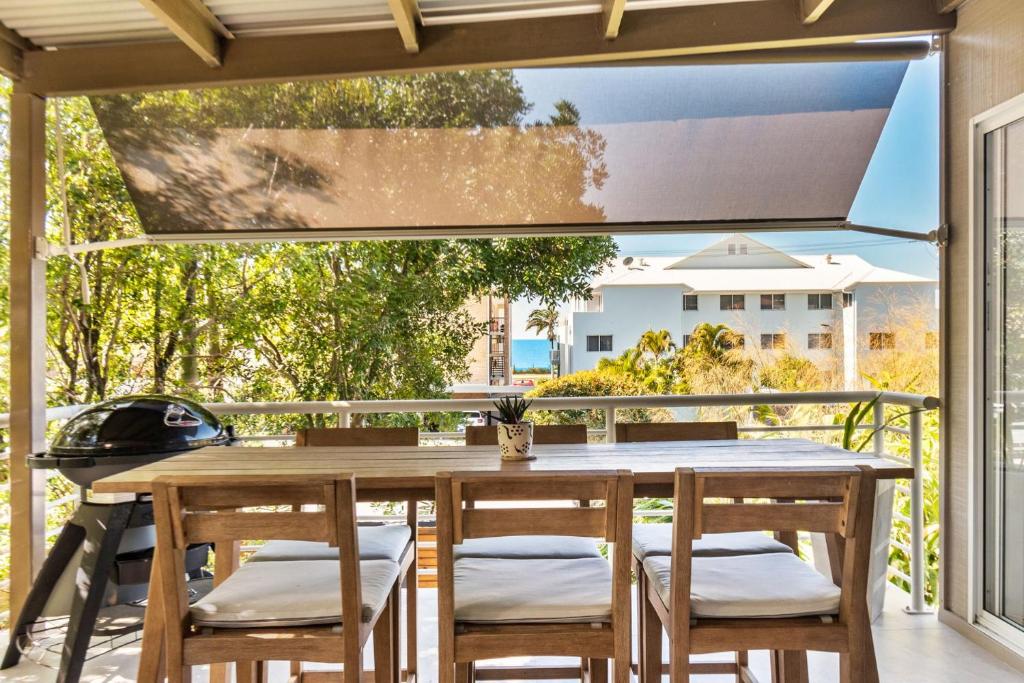 a wooden table and chairs on a patio with a window at By the beach 2 beach side 3 bedroom 2 bathroom home in Alexandra Headland
