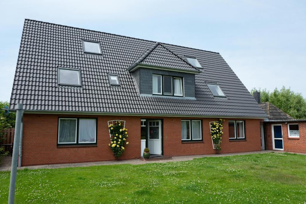 une maison avec deux fenêtres et un toit dans l'établissement Haus Kölfhamm, à Sankt Peter-Ording