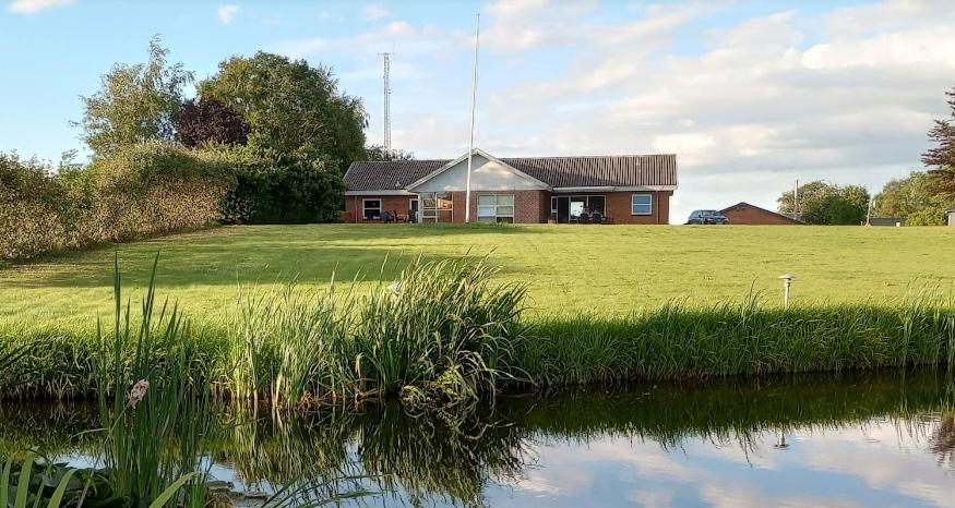 una casa en un campo con un estanque delante en Annex88 B&B, en Fårvang