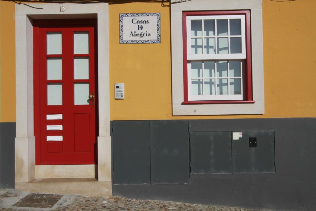 a building with a red door and a window at Casas da Alegria in Coimbra