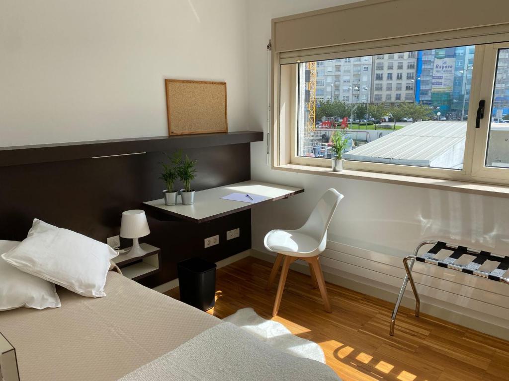 a bedroom with a bed and a desk and a window at Hospedería San Froilan in Lugo