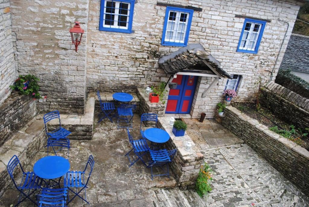 an outdoor patio with blue tables and chairs in front of a building at Orestis House in Ano Pedina
