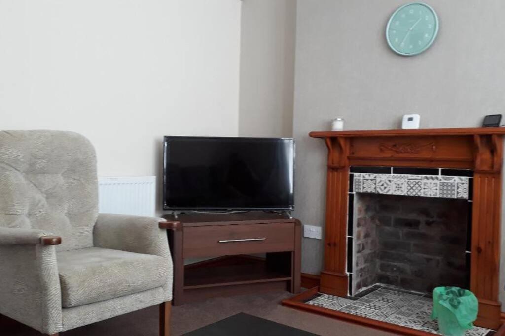 a living room with a television and a fireplace at Porthcawl House Near Beach With Extensive Parking in Porthcawl