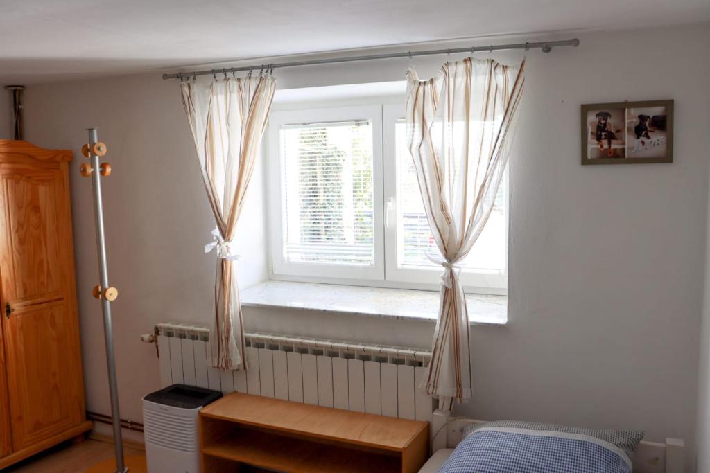 Un dormitorio con una ventana con cortinas. en LITTLE FOREST RANCH, NATUR PUR MIT REITMÖGLICHKEIT en Duga Resa