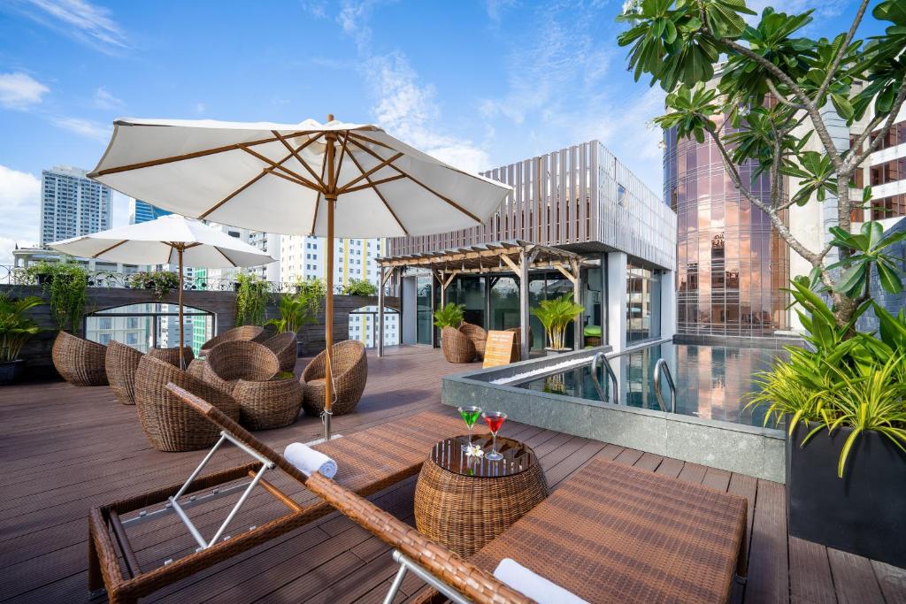 a patio with chairs and an umbrella and a pool at Se&ntilde;orita Boutique Hotel in Da Nang