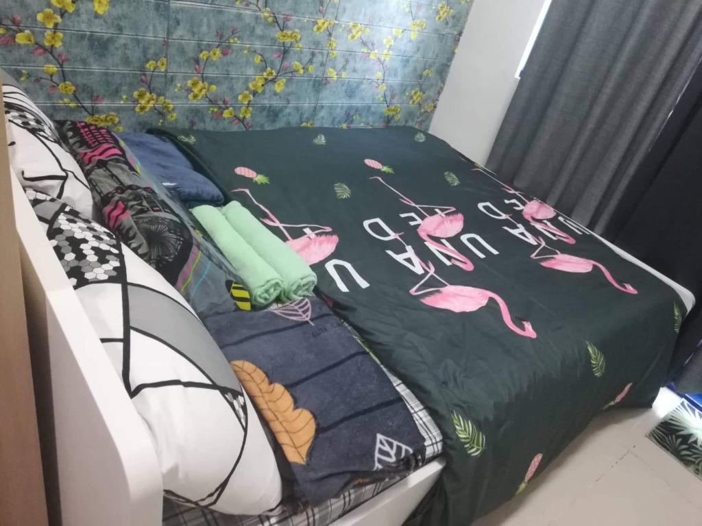 a bed with a black blanket with pink flamingos on it at Aj booking in Manila
