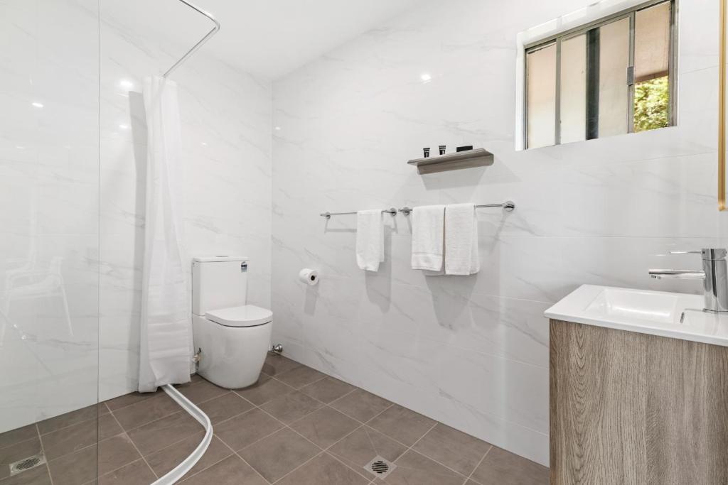 a white bathroom with a toilet and a sink at Lemon Tree Passage Motel in Lemon Tree Passage