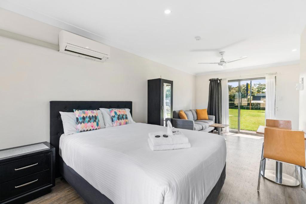 a bedroom with a large white bed and a living room at Lemon Tree Passage Motel in Lemon Tree Passage
