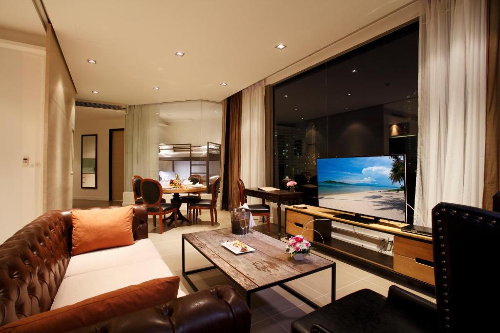 een woonkamer met een bank en een groot televisiescherm bij Pattaya Modus Beachfront Resort in Noord Pattaya