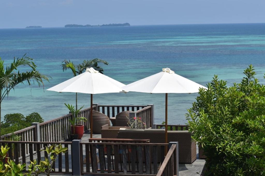 dos sombrillas blancas en una terraza con el océano en The Secret Karimunjawa en Karimunjawa