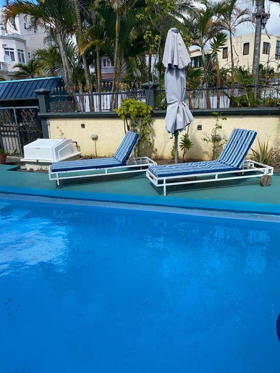 una piscina con 2 tumbonas y una sombrilla en Gardenia Villa en Mont Choisy